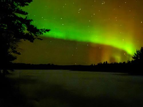 an aurora dances in the sky over a lake at Holiday Home Jolmalompolo by Interhome in Raanujärvi