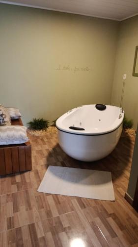 a white bath tub in a room with a bed at Vinhas das Grutas in Soledade