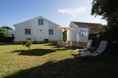 a house with a yard with two chairs and an umbrella at Quinta de São Caetano - São Miguel Açores in Populo