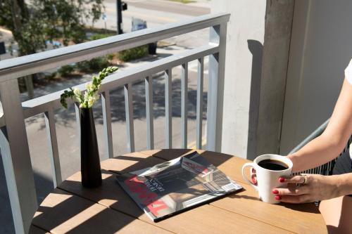 a woman sitting at a table with a cup of coffee at Mint House Tampa Downtown by Kasa in Tampa