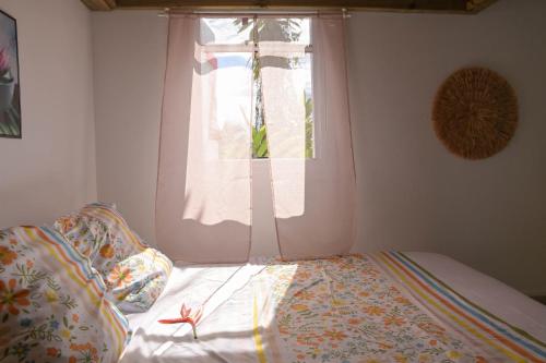ein Schlafzimmer mit einem Bett und einem Fenster mit einer Bettdecke in der Unterkunft Sikriyé in Petit-Bourg