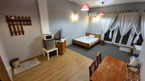 a room with a table and a bed and a television at KEISA APARTRooms in Nowy Sącz
