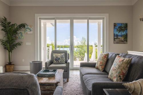 a living room with a couch and a chair at Springtide House -Dock & Home w Pool in Stock Island
