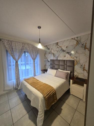 a bedroom with a large bed and a stone wall at The Blyde Luxury Apartments in Pretoria