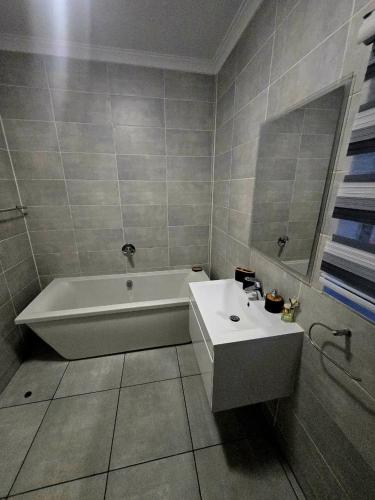 a bathroom with a white tub and a sink at The Blyde Luxury Apartments in Pretoria