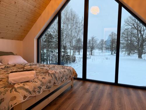 a bedroom with a bed and large glass windows at OAK House domek z balią w Serskim Lesie in Las Dalny