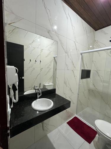 a white bathroom with a sink and a mirror at Hotel Carrão in São Paulo