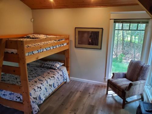 a bedroom with bunk beds and a chair and a window at Sunset Bay Lodge in Abbeyville