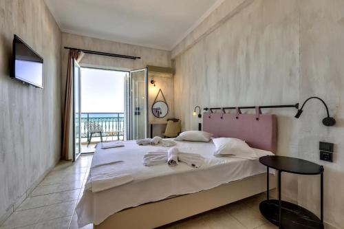 a bedroom with a large bed and a large window at Argassi Beach Hotel - Adults Only in Argassi