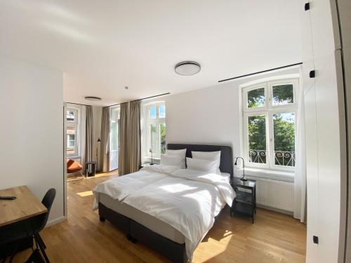 a bedroom with a bed and a desk and windows at Backbord Geesthacht in Geesthacht