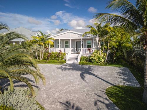 a white house with palm trees and a driveway at Seagate House -Waterfront w Dock in Key West