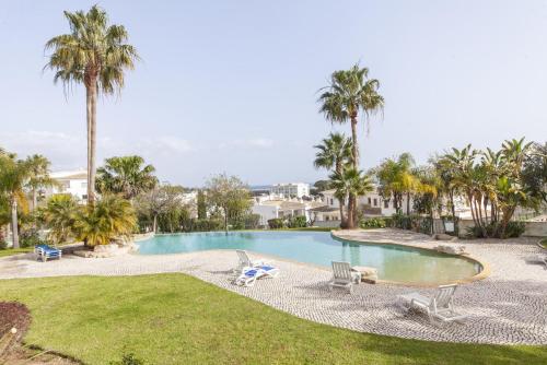 a swimming pool with two chairs and palm trees at A49 - Anastasia Apartment in Lagos in Lagos
