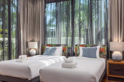 two beds in a room with large windows at VILLA PULAU 3 bedroom Baan Bua Estate in Nai Harn Beach