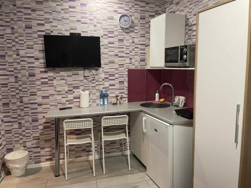 a kitchen with a sink and a counter with two stools at Apartamenty Konopnicka in Bydgoszcz