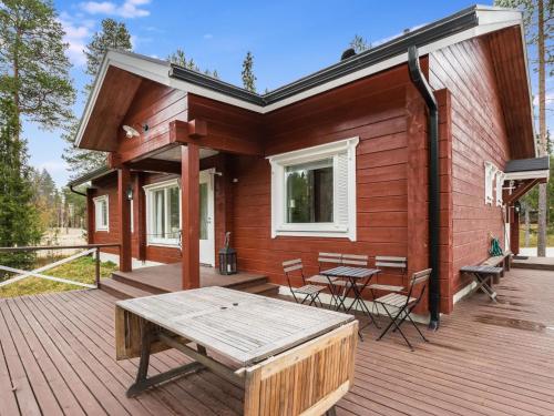a cabin with a wooden deck with a table and chairs at Holiday Home Isokuru 3 by Interhome in Pyhätunturi