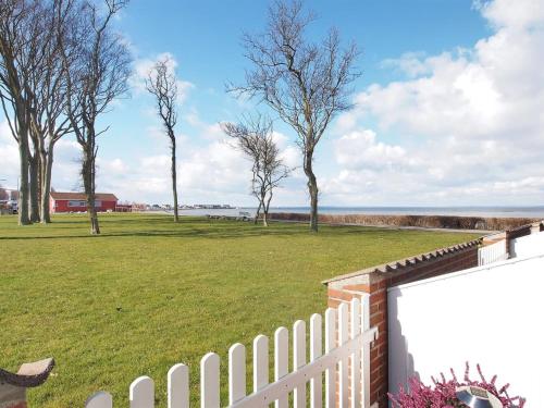 a white fence with trees in a field at Apartment Elevus - 10m from the sea by Interhome in Bogense