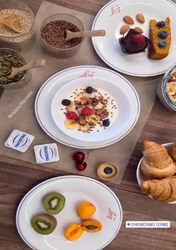a wooden table with plates of food on it at Hotel Lory My Wellness SPA in Chianciano Terme