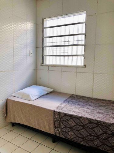 a small bed in a room with a window at Casa três quartos em condomínio in Garanhuns