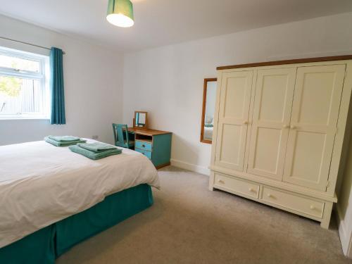 a bedroom with a bed and a large white cabinet at Hafod Wen in Pentraeth