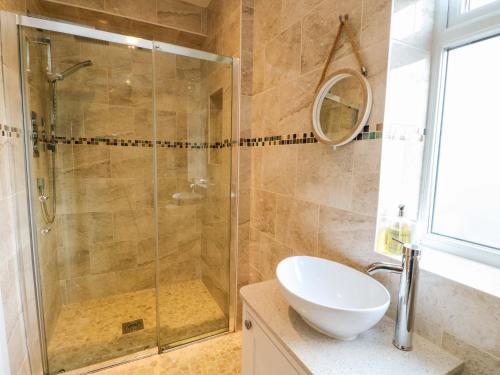a bathroom with a glass shower and a sink at Hafod Wen in Pentraeth