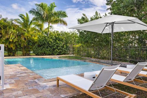 a pool with two chairs and an umbrella at Capmar House -Huge Home & Pool in Stock Island