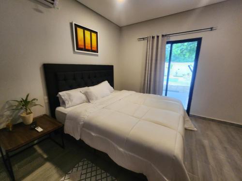 a bedroom with a large white bed and a window at La Calma San Bernardino in San Bernardino