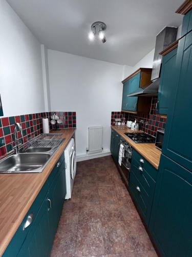 a kitchen with green cabinets and a sink at Chill At Gee's in Nottingham
