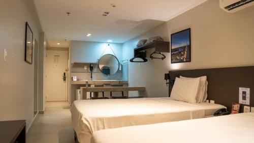 a bedroom with two beds and a table in it at Quality Suítes João Pessoa in João Pessoa