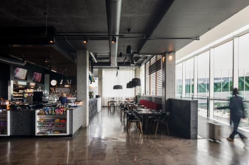 a person walking through a restaurant with tables and chairs at Alt Hotel Halifax Airport - In Terminal in Enfield