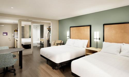a hotel room with two beds and a desk at LivSmart Studios By Hilton Kokomo in Kokomo