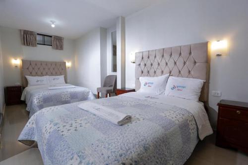 a hotel room with two beds with white sheets at Witobi Hostal in Cajamarca