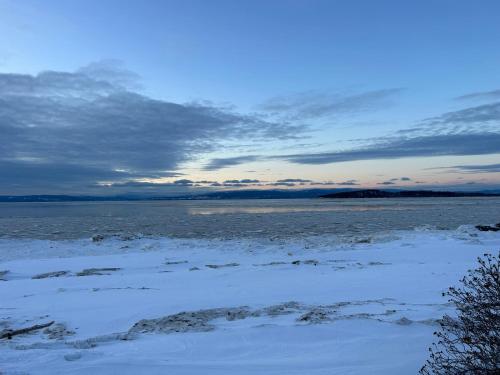 a view of a body of water with snow at Auberge Foin de mer in Kamouraska