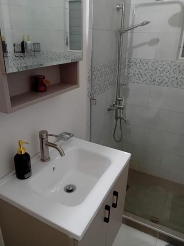 a white bathroom with a sink and a shower at Cozy Escape 876 Secure 2BR with AC, Parking & near Beaches in Portmore