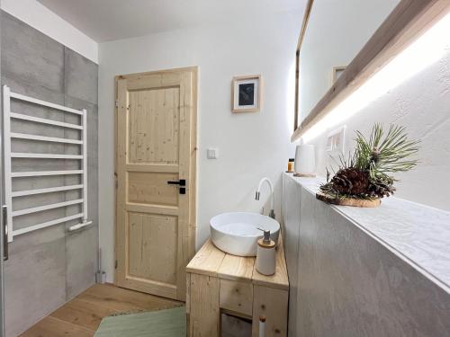 a bathroom with a white sink and a door at Panorama Tatry Apartment in Jezersko