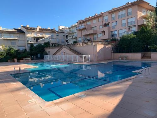 a swimming pool with blue water in front of some buildings at Studio Saint-Tropez Heraclée in Saint-Tropez