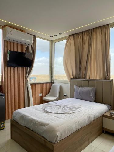 a bedroom with a bed in a room with windows at Cloud pyramids view inn in ‘Ezbet `Abd el-Ḥamîd