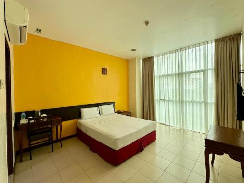a bedroom with a bed and a desk and a yellow wall at GRAND FAR EAST HOTEL SDN BHD in Masai