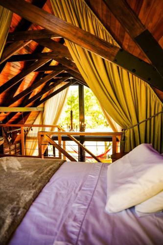 a bedroom with a bed in a room with curtains at Relaggio Chalet Encantado - Cristo Protetor in Encantado