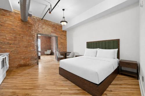 a bedroom with a bed and a brick wall at Tri Century Mill Suites in Carleton Place