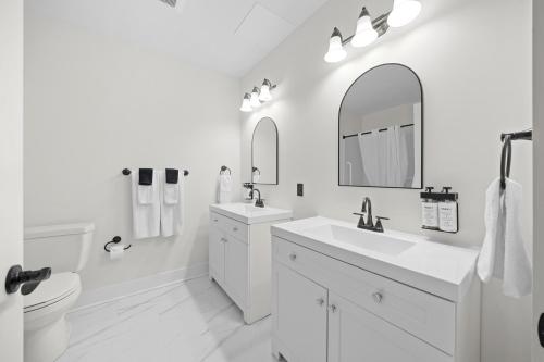 a white bathroom with two sinks and a toilet at Tri Century Mill Suites in Carleton Place