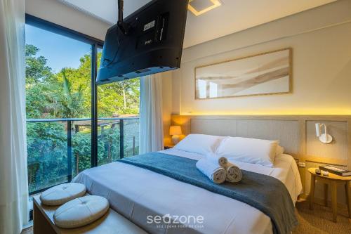 a bedroom with a bed and a large window at Studio in center of Rosa, rooftop w/ pool RSO0031 in Imbituba