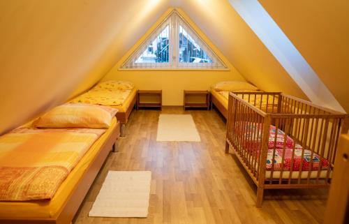 a attic bedroom with three beds and a window at Vanilka in Liptovský Trnovec