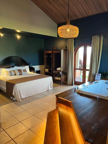 a bedroom with a bed and a tub in it at Tenondé Park Hotel in São Miguel das Missões