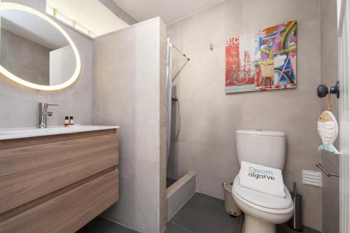 a bathroom with a toilet and a sink and a mirror at A27 - Caracol Corner Studio in Lagos in Lagos