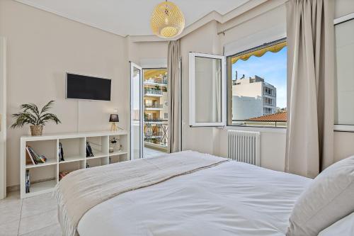 a white bedroom with a large bed and a window at Fabulous central apartment close to the sea! in Chalkida