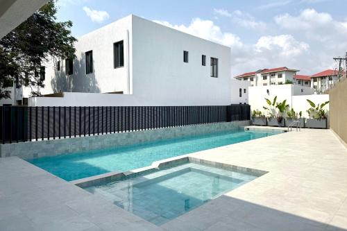 a swimming pool in front of a white house at The N3st at Giffard Park in Burma Camp