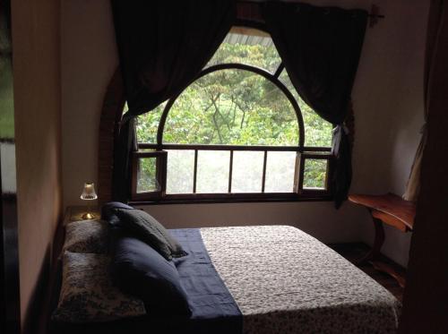 a bedroom with a bed and a large window at Casa Cafetal Coatepec in Coatepec