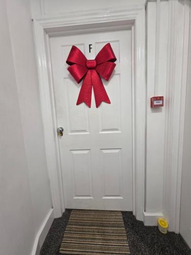 a white door with a red bow on it at Vibrant - Free Parking - Sleeps 6 M20-FolkestoneCentralStation in Folkestone