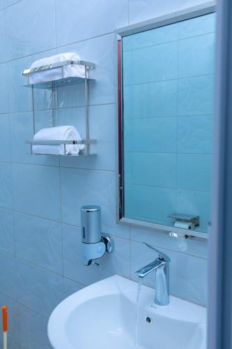 a white bathroom with a sink and a mirror at Fort Arch Eco-Lodges in Fort Portal
