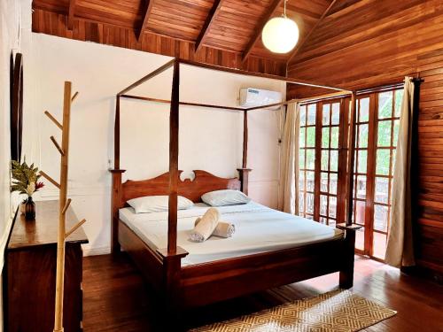 a bedroom with a four poster bed in a house at Hotel Mandacarú Puerto Viejo in Puerto Viejo